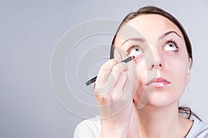 Woman Applying Eyeliner Makeup While Looking Up