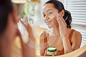 Woman applying face cream during morning routine