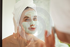 Woman applying face pack while looking in the mirror