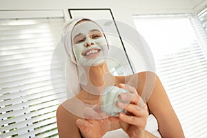 Woman applying face pack while looking in the mirror