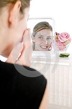 Woman applying facepack in mirror