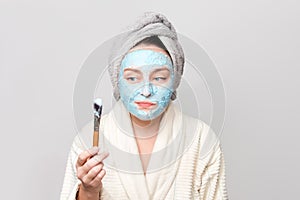 Woman applying facial clay mask at spa salon or at home, skincare theme. Face mask, spa beauty treatment with copy space