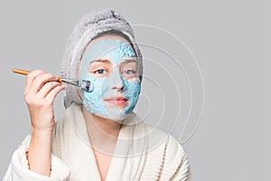 Woman applying facial clay mask at spa salon or at home, skincare theme. Face mask, spa beauty treatment with copy space