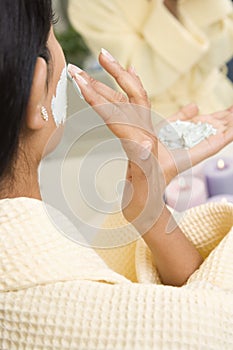 Woman applying facial scrub.