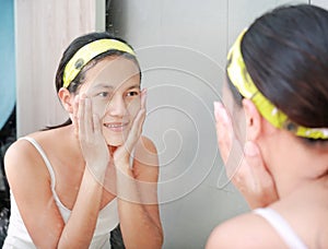 Woman applying foam cream to face reflect with bathroom mirror