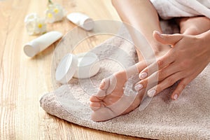 Woman applying foot cream on towel, closeup.