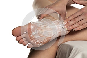 Woman applying foot mask on her sole fee