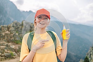 Woman applying insect repellent against mosquito and tick on her hand during hike in nature top mountain. Skin