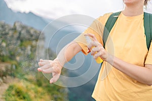 Woman applying insect repellent against mosquito and tick on her hand during hike in nature top mountain. Skin