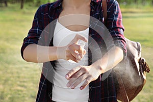 Woman applying insect repellent onto arm outdoors, closeup