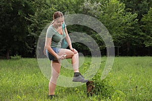 Woman applying insect repellent onto leg in park. Tick bites prevention