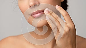 Woman applying lip balm over grey background