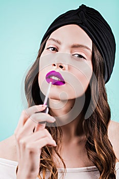 Woman applying lipstick. Beautiful girl makes makeup. Fashion, purple color, fashion portrait.