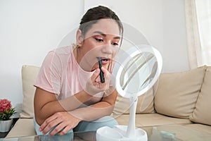 Woman applying lipstick in front of mirror