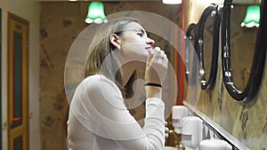 Woman applying lipstick in hostel toilet