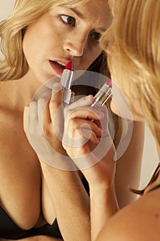 Woman applying lipstick in mirror