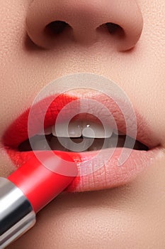 Woman applying lipstick. Model painted red lips