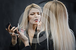 Woman applying lipstick looking to the mirror