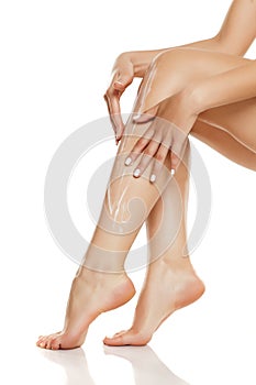 Woman applying lotion on her long legs