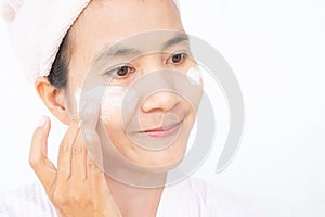 Woman applying lotion skin serum cream on face with smile after shower. Moisturizer skin care for moisturized reduce wrinkles and
