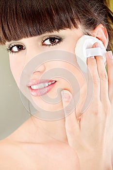 Woman applying make up with cosmetic sponge