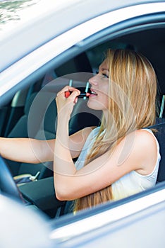 Woman applying make-up while driving car.