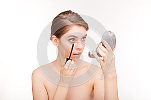 Woman applying mascara on her eyelashes