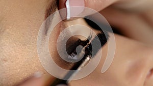 Woman applying mascara on her long eyelashes. Black. Closeup