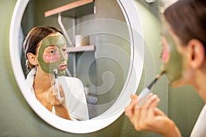 Woman applying mask on her face in the bathroom