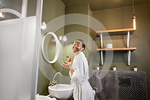 Woman applying mask on her face in the bathroom
