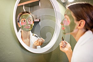 Woman applying mask on her face in the bathroom