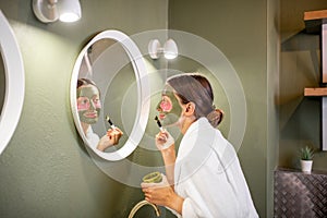 Woman applying mask on her face in the bathroom