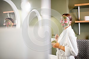 Woman applying mask on her face in the bathroom