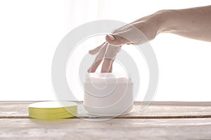 Woman applying moisturizer cosmetic on her hands. White background and empty copy space