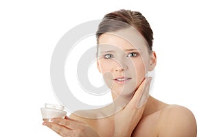 Woman applying moisturizer cream on face