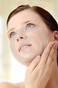 Woman applying moisturizer cream on face