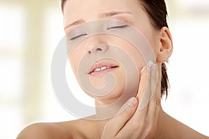 Woman applying moisturizer cream on face