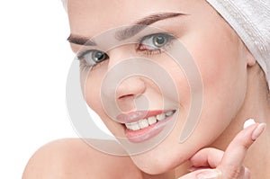 Woman applying moisturizer cream on face