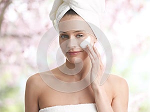 Woman applying moisturizer cream on face