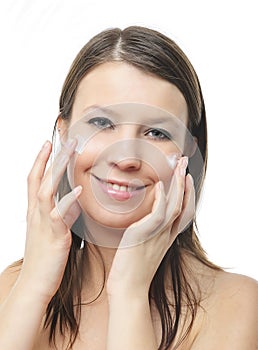 Woman applying moisturizer cream on face