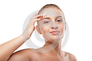 Woman applying moisturizer cream on face isolated