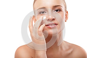 Woman applying moisturizer cream on face isolated