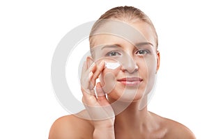 Woman applying moisturizer cream on face isolated