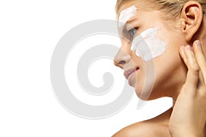 Woman applying moisturizer cream on face isolated