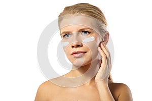 Woman applying moisturizer cream on face isolated