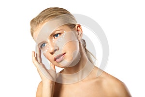 Woman applying moisturizer cream on face isolated