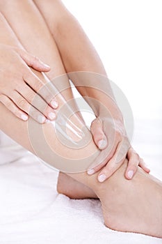 Woman applying moisturizer cream on the legs