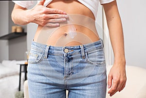 Woman applying moisturizer cream lotion on belly