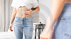 Woman applying moisturizer cream lotion on belly