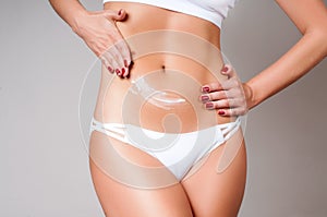 Woman applying moisturizer cream lotion on belly. Woman wear white underwear